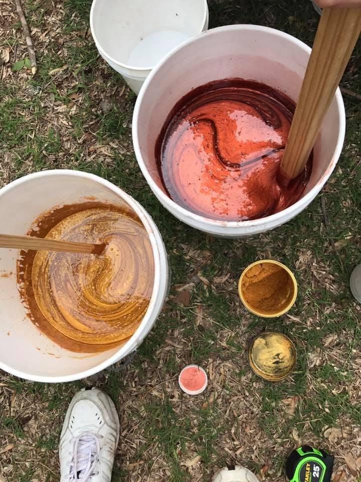 Buckets of hand-mixed custom paint pigment in gold and burnt-orange tones