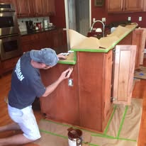 Painter taping off a wood kitchen island before refinishing