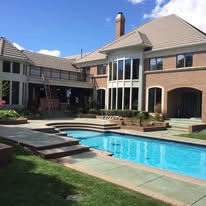 Large brick home exterior with a pool
