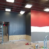 Commercial retail space mid-paint with a half-finished red accent wall