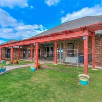 Pergola finished in a rust-red stain with landscaping around the patio