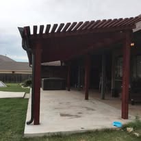 Bare unfinished wood pergola over a concrete patio before staining